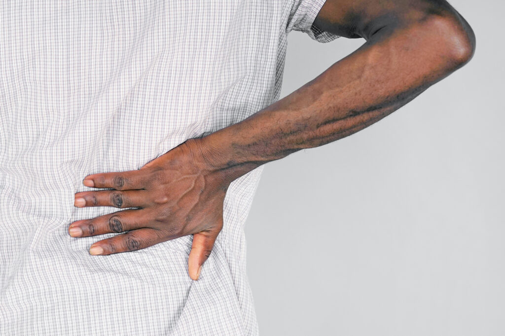 Close-up of a person holding their lower back in pain